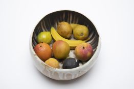 A GLAZED CERAMIC BOWL FILLED WITH FRUIT