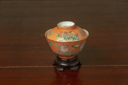 AN ORANGE GROUND FAMILLE ROSE PORCELAIN BOWL AND COVER