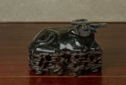 A BLACK GLAZED MODEL OF A RECUMBENT BUFFALO