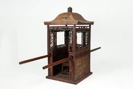 A CARVED AND POLYCHROME DECORATED SEDAN CHAIR