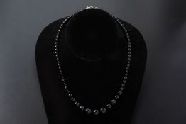 A GRADUATED BLACK GEMSTONE NECKLACE AND EARRING SET