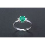 AN EMERALD AND DIAMOND THREE STONE RING