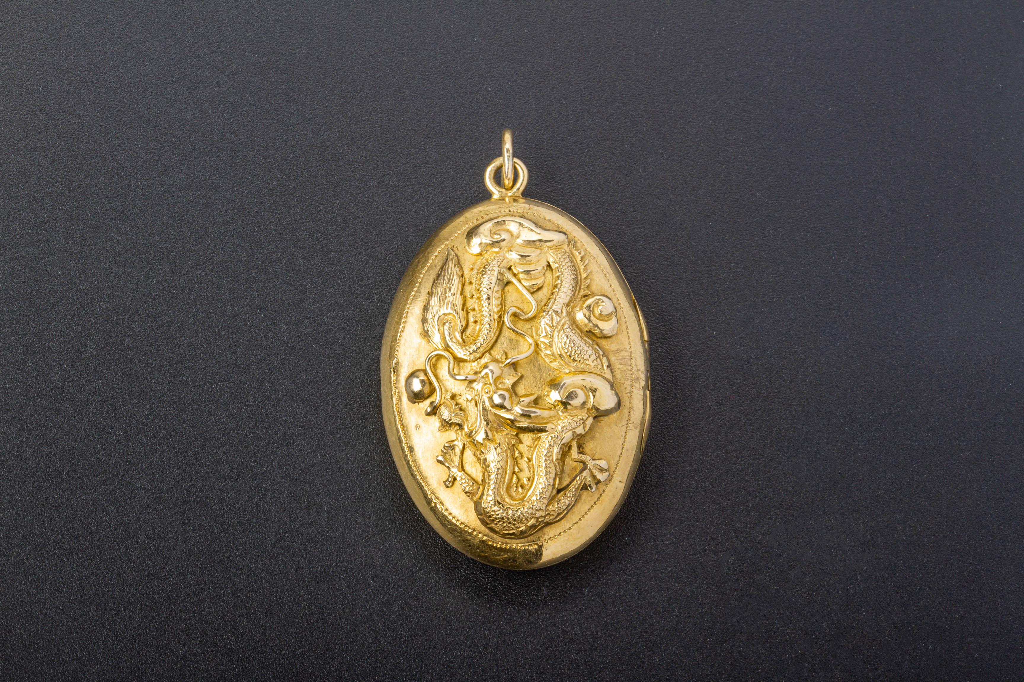 AN 18K GOLD DRAGON LOCKET