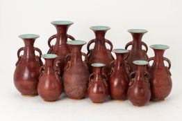 A SET OF TEN GRADUATED PEAR SHAPED TWIN HANDLED VASES