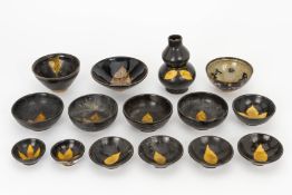 A GROUP OF FIFTEEN BLACK GLAZED AND LEAF DECORATED ITEMS