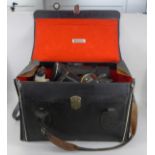 A leather camera bag containing a Praktica Super TL 35mm film camera and equipment including