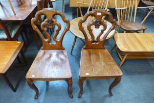A pair of Victorian carved oak armorial hall chairs