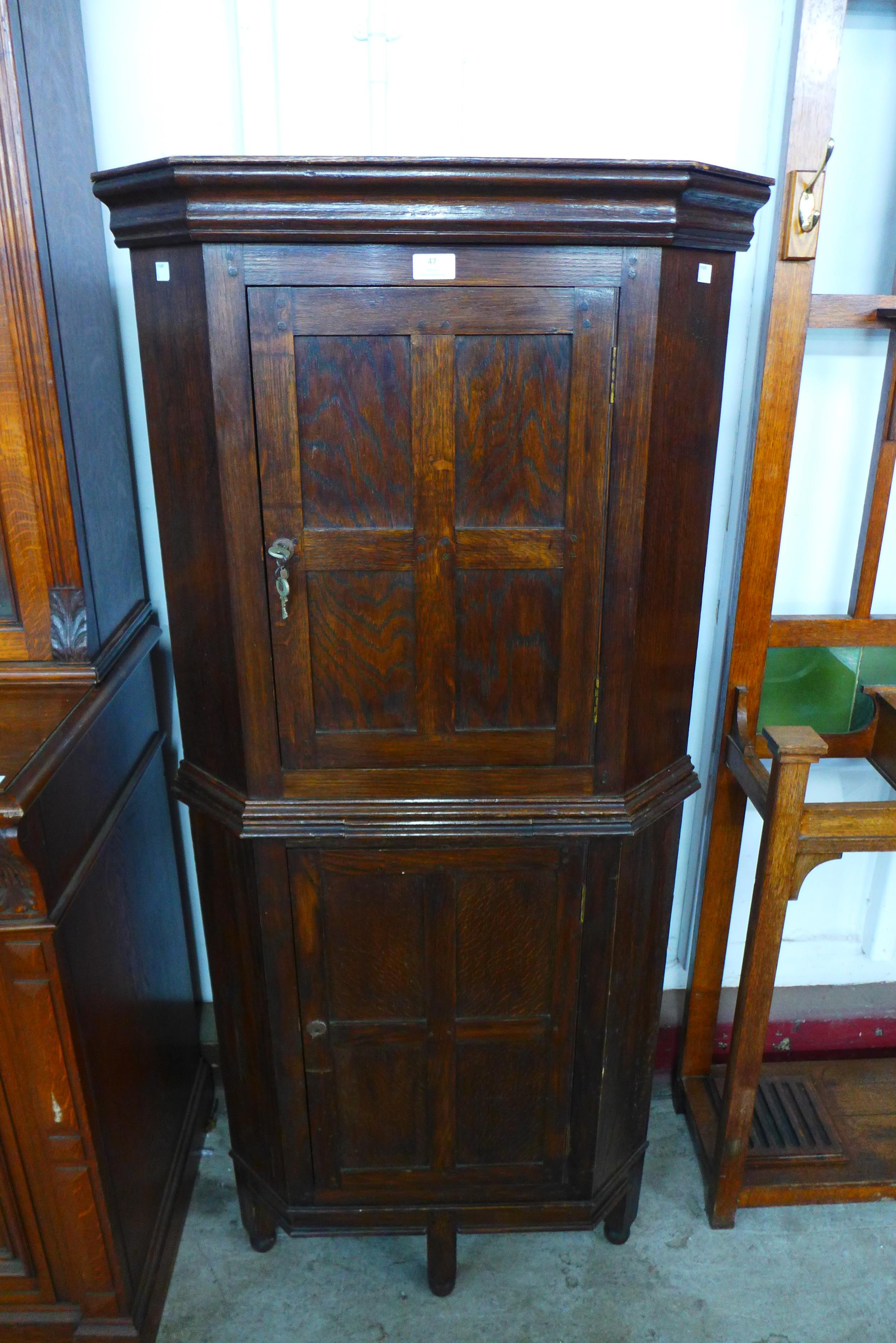 An Arts and Crafts Cotswold School oak freestanding corner cupboard