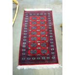 A Pakistani hand knotted red ground Bokhara rug, 140 x 80cms