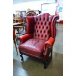 A mahogany and red leather Chesterfield wingback armchair