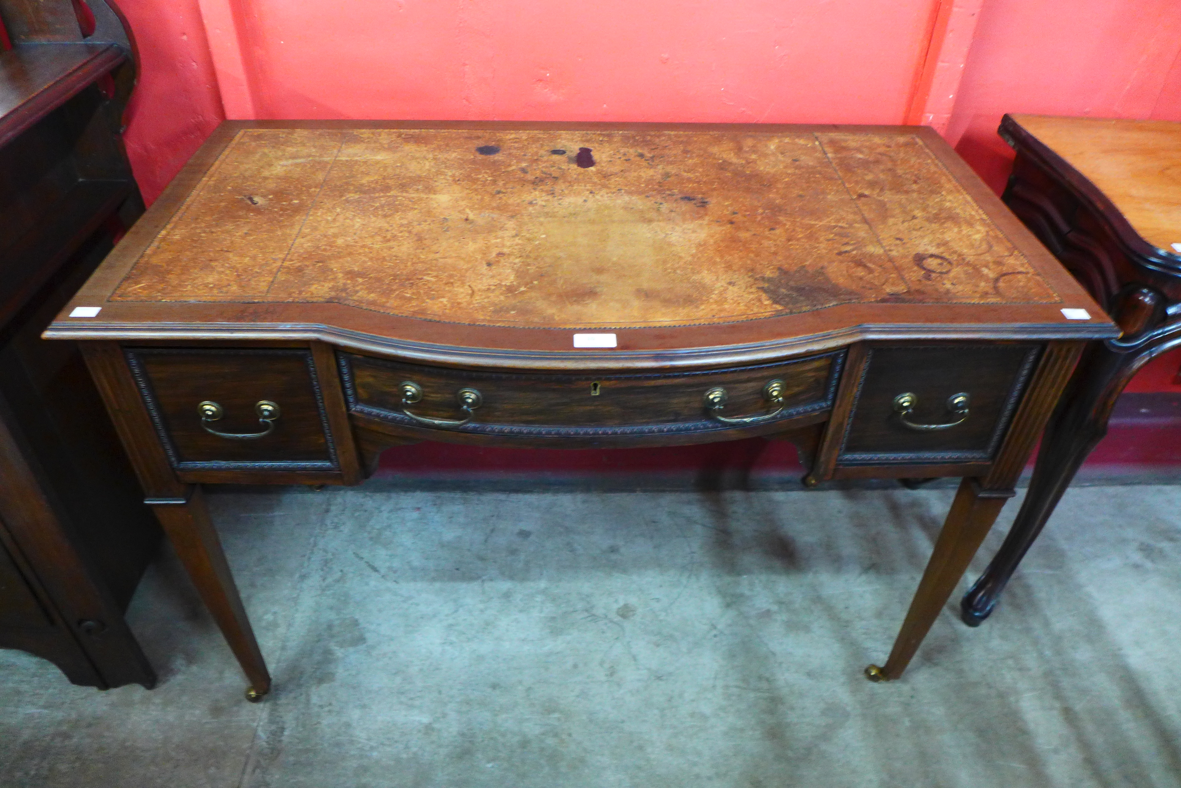 An Edward VII mahogany and leather topped bow centre writing table