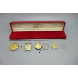 An Omega wristwatch box, a lady's Omega wristwatch head and three movements and dials