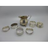 A silver cream jug and six silver napkin rings, a/f, 165g