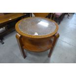 An Art Deco walnut bergere two tier circular coffee table