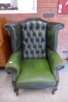 A green leather Chesterfield wingback armchair