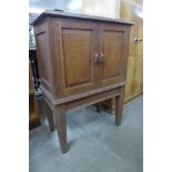 A small Cotswold School oak two door cabinet on stand