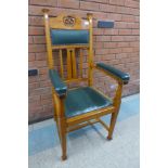 An Arts and Crafts carved oak and green leather armchair