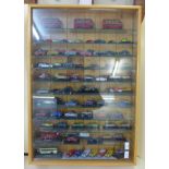 A display cabinet with die-cast model vehicles, many on plastic mounts (approximately 95)