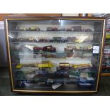 A display cabinet with die-cast model vans and lorries (approximately 55)