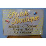 A painted wooden Stitch Boutique advertising sign