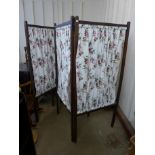 A pair of stained pine framed folding screens