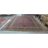 A fine hand knotted Persian red ground Mashad rug, 385 x 308cms