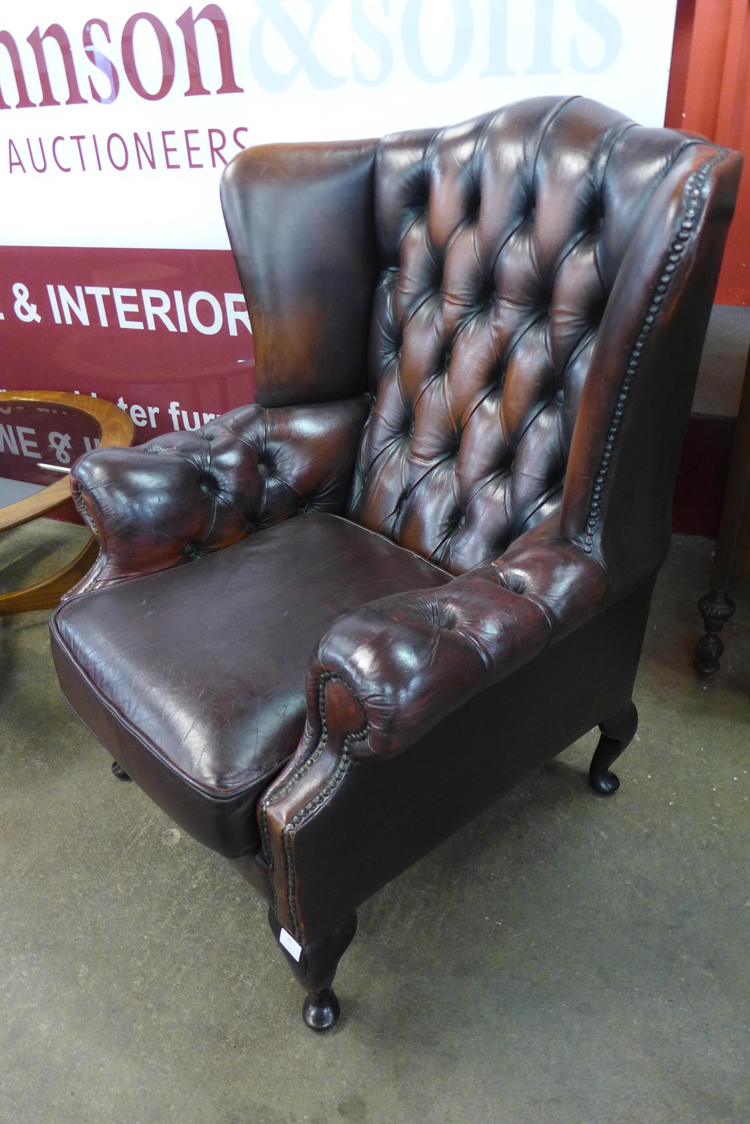 A mahogany and chestnut brown leather Chesterfield wingback armchair