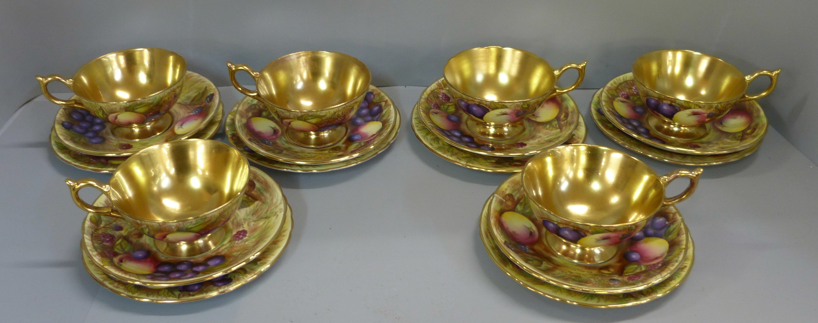 A set of six Aynsley cups, saucers and tea plates, decorated with fruit and berries in gold rim