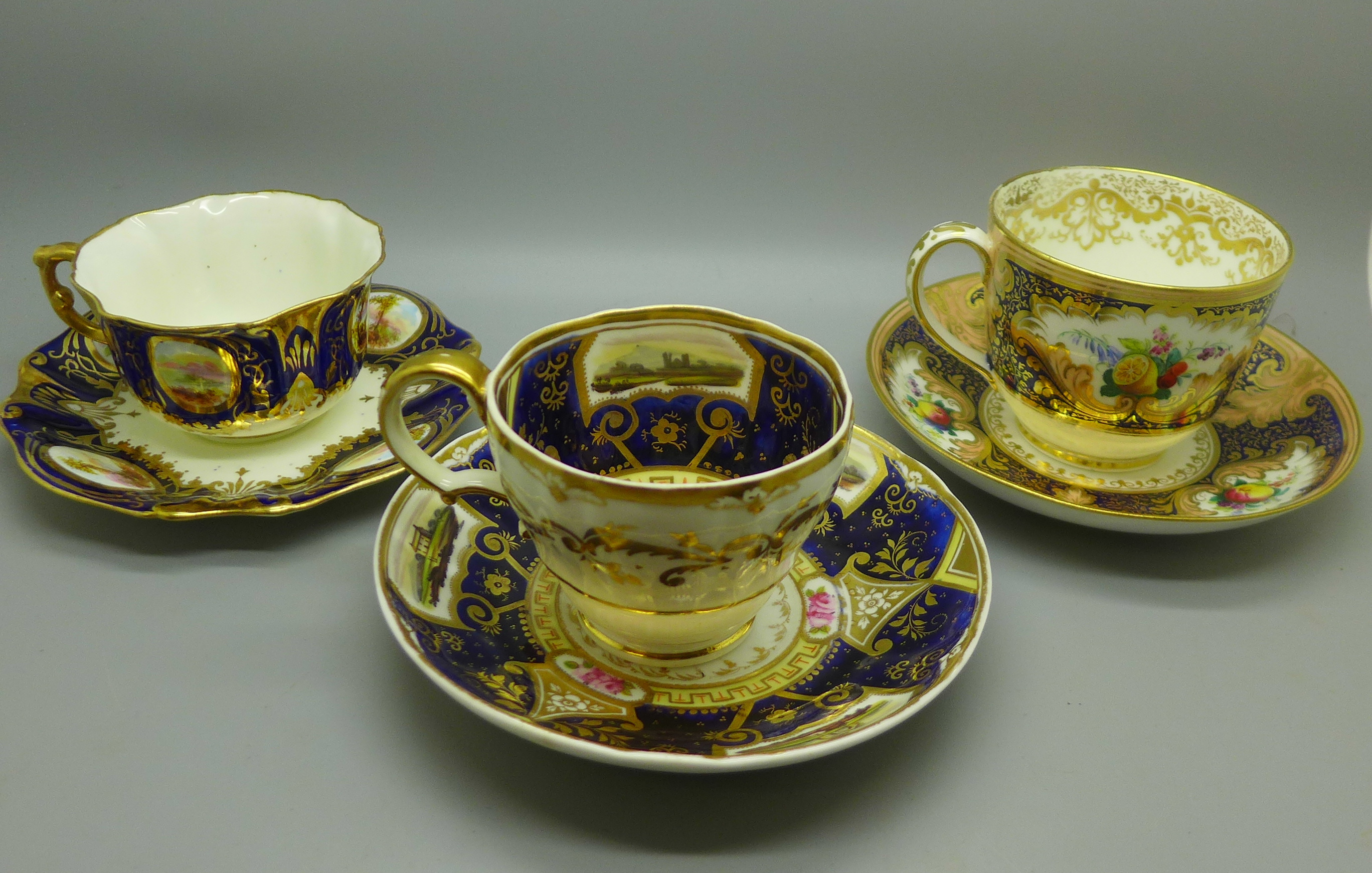 Three 18th/19th Century cups and saucers, two with painted panels of landscapes, one decorated