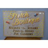A painted wooden Stich Boutique advertising sign