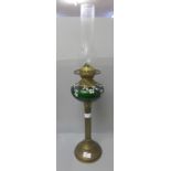 A brass oil lamp with green glass reservoir