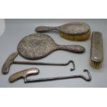 Two silver handled boot pulls and a silver backed vanity set, mirror and two brushes, mirror a/f