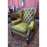 A mahogany and olive green leather Chesterfield wingback armchair