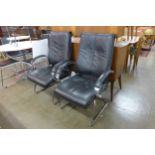 A pair of black leather and chrome armchairs