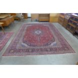 A large Persian hand knotted red ground Kashan rug, 409 x 206cms