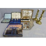Two brass candlesticks and a collection of cased plated flatware and a Cutlass three piece drinks