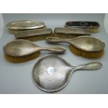 Six silver backed brushes and a hand mirror