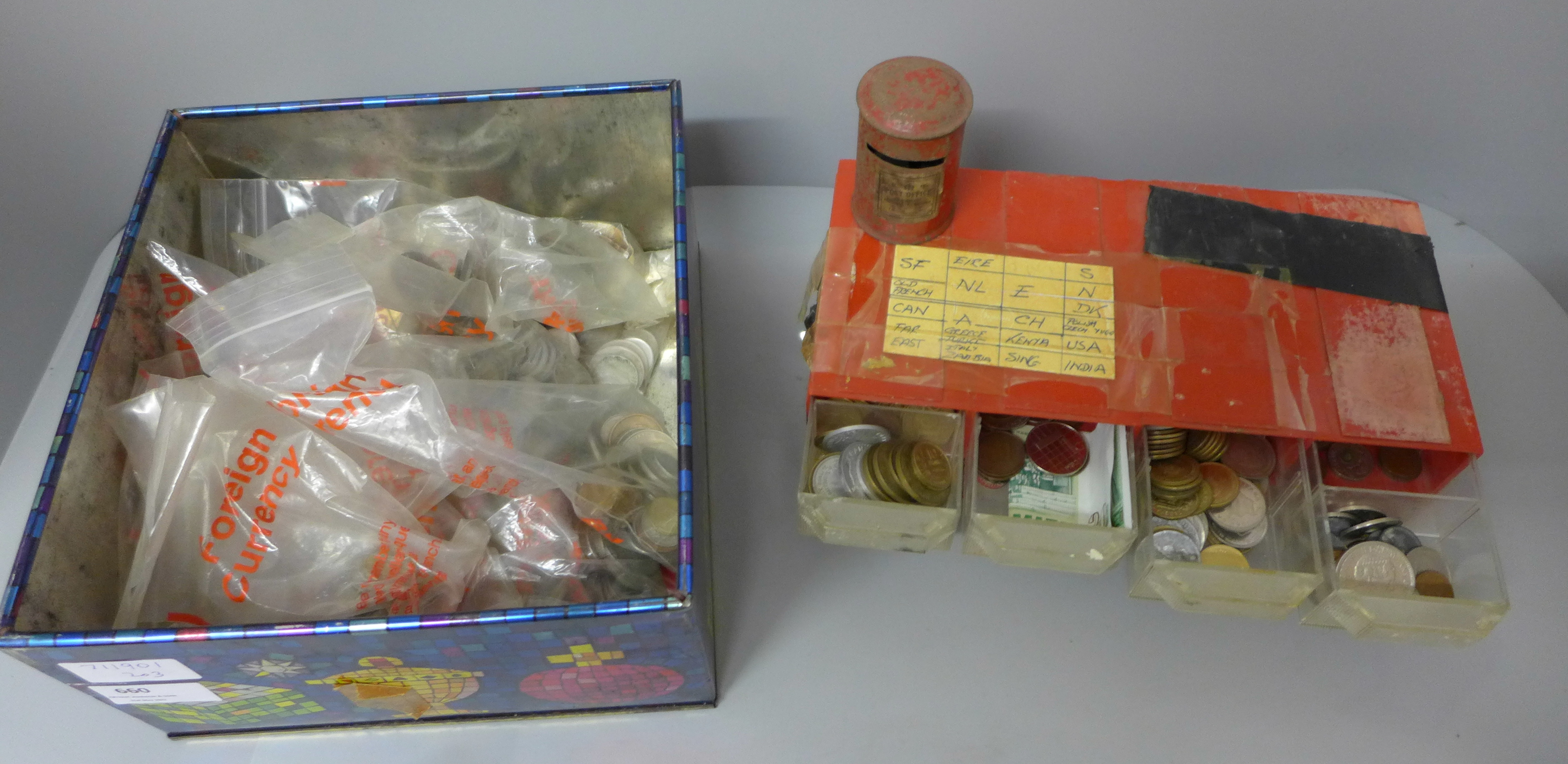 An eight drawer plastic cabinet with sorted foreign coins and a tin of coins