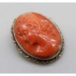 A carved coral cameo brooch set in silver