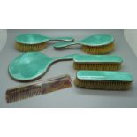 A silver and enamel dressing table set, mirror, four brushes and a comb