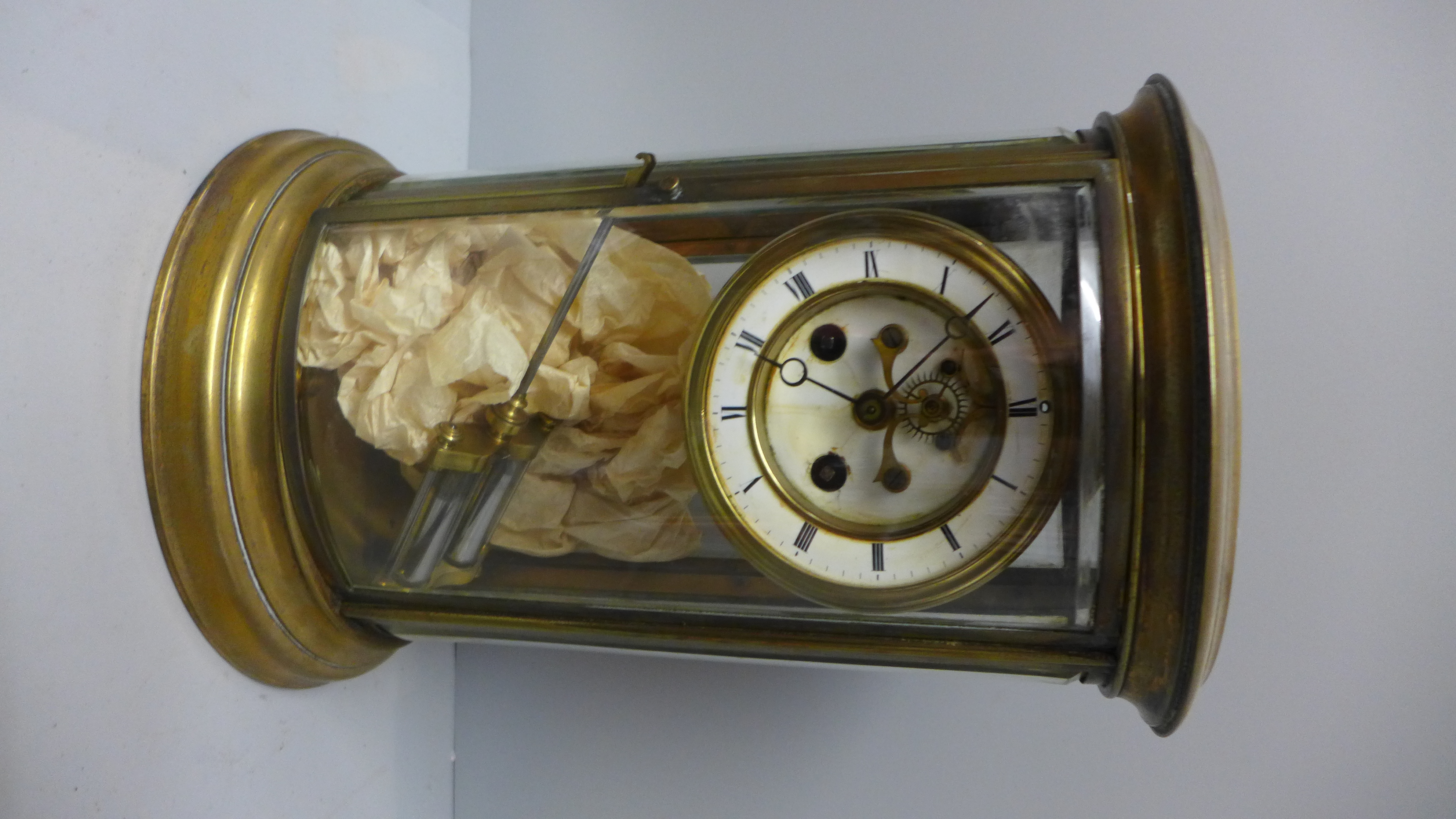 A brass and four glass table clock of oval form by Samuel Marti, striking on a bell and with visible