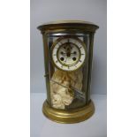 A brass and four glass table clock of oval form by Samuel Marti, striking on a bell and with visible