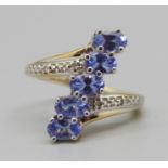 A silver gilt, five stone tanzanite ring with diamond accents, L