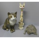 A wooden figure of a cat with floral design, a ceramic cat figure and bronze tortoise water feature