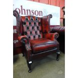 A mahogany and red leather Chesterfield wingback armchair