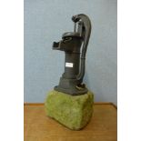 A cast iron water pump, on stone plinth