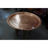 An Egyptian copper coffee table, on carved hardwood folding base