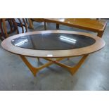 An oval teak and glass topped coffee table