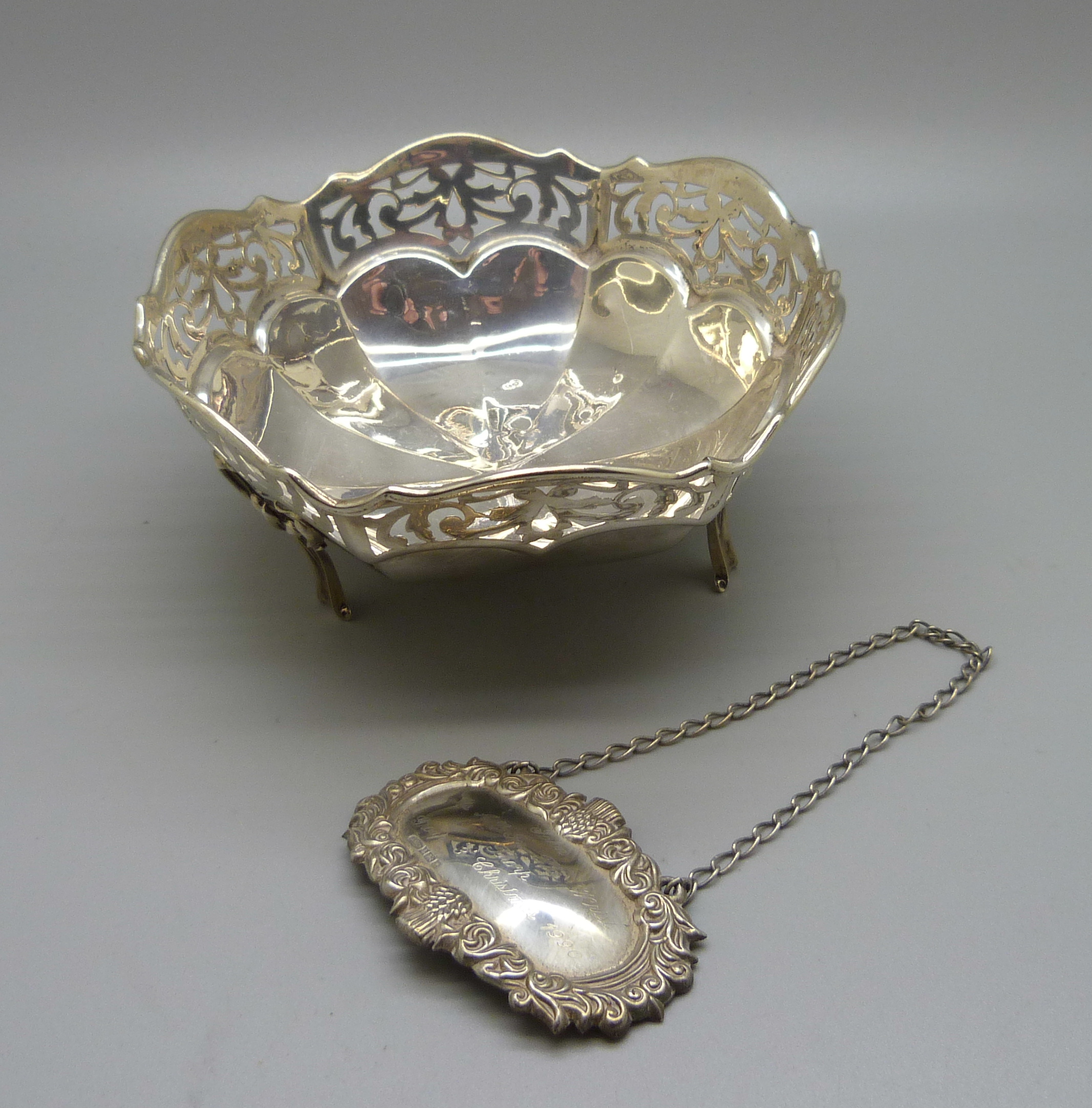 A pierced silver dish and a silver spirit label with inscription, 139g