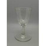 A large round funnel bowl wine glass, petal faceting to bowl, with faceted stem and flared foot with